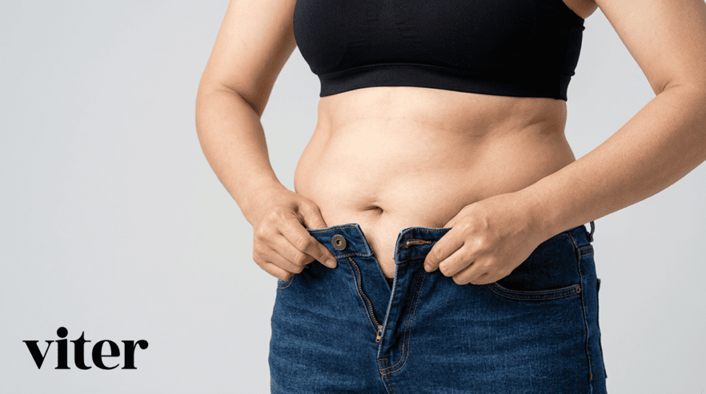 청바지 단추가 잠기지 않아 손으로 허리 뱃살을 잡고 고민하는 모습